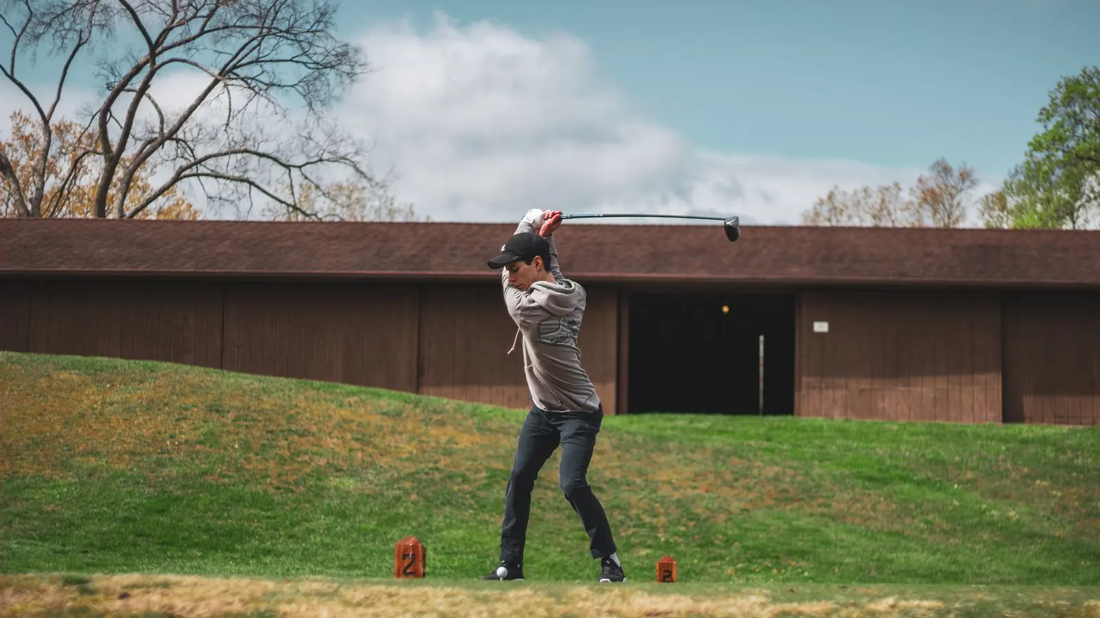 Golfer at the top of his backswing on a tee box on a clear day